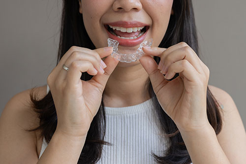 Woman smiling while putting on clear aligners
